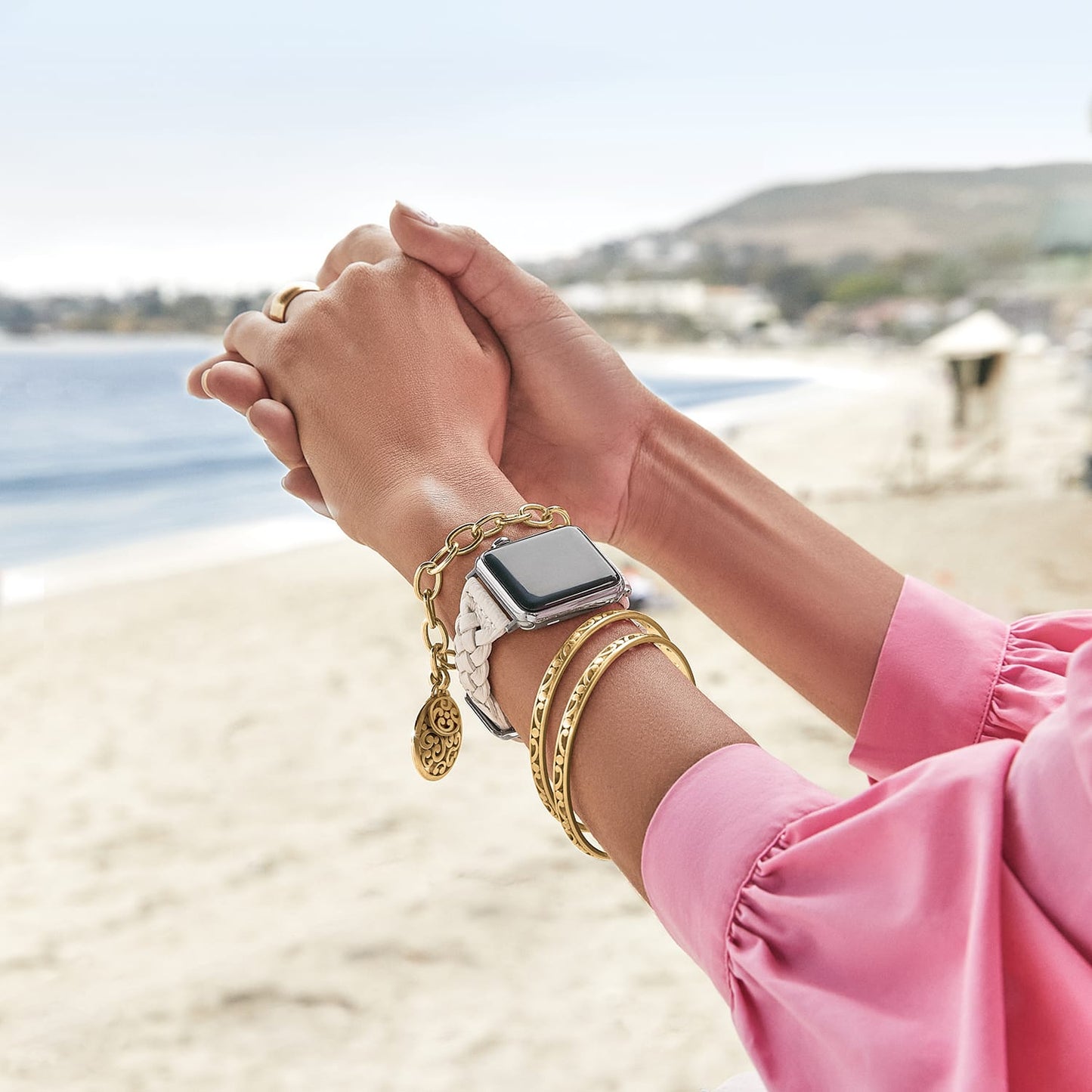Model wearing a Brighton white braided watch band with coordinating Brighton accessories including gold-plated bangles and charm bracelet