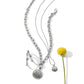 Brighton silver-plated jewelry set styled with a yellow craspedia flower, featuring chain necklaces, scroll pendants, and hoop earrings