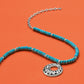 Brighton beaded necklace with dyed howlite beads, silver-plated chain, and open scroll pendant on an orange background
