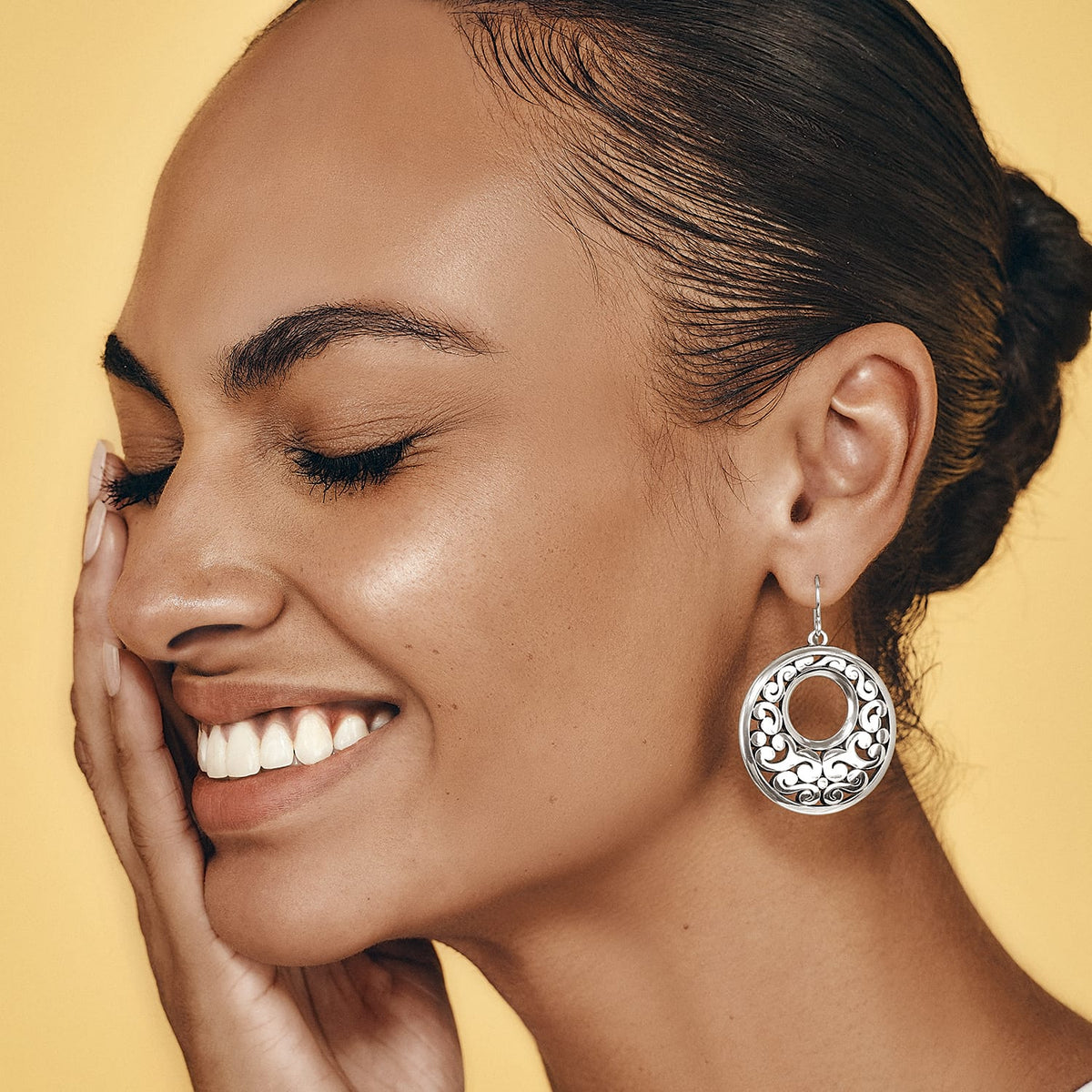 Model wearing a Brighton silver-plated drop earring with circular openwork scroll design and polished finish