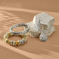 Brighton silver-plated bangle, teardrop earrings, and disk bead bracelet styled with stone blocks on tan background