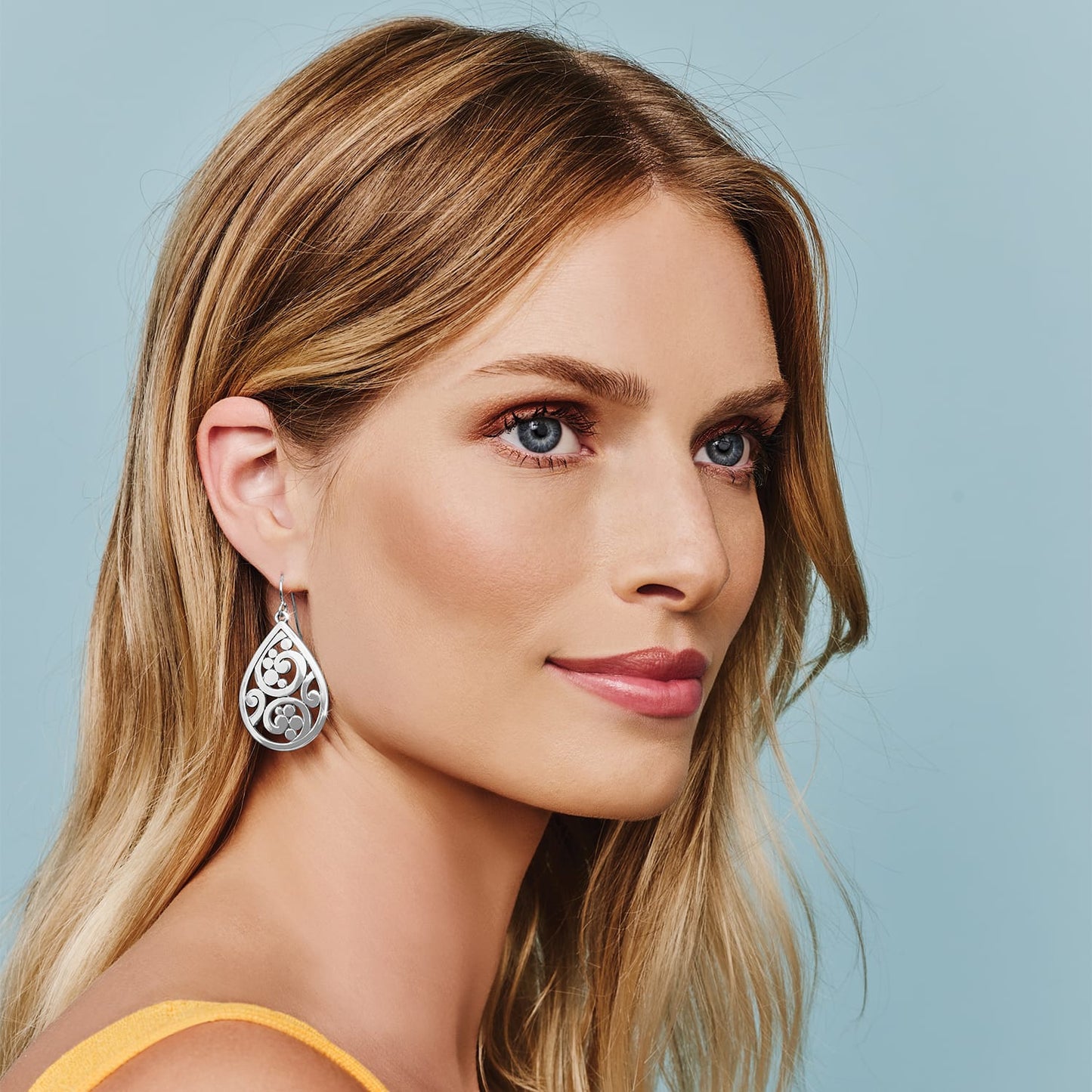 Model wearing a Brighton silver-plated teardrop earring with openwork scroll and dot design