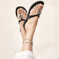 Model wearing Brighton black thong sandals with silver-plated medallion accents, paired with a silver-plated charm anklet