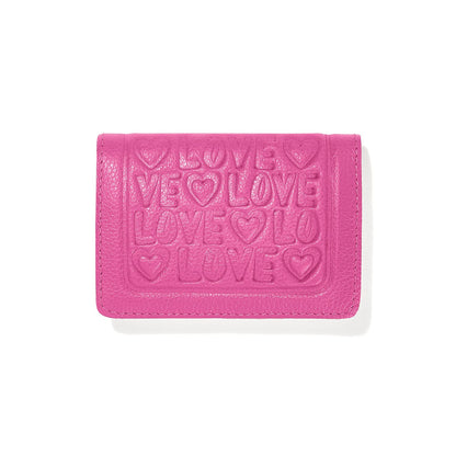 Brighton pink leather wallet with embossed LOVE lettering and heart motifs on the front flap on a white background