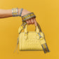Model with a Brighton yellow leather handbag featuring embossed LOVE print and matching webbed shoulder strap
