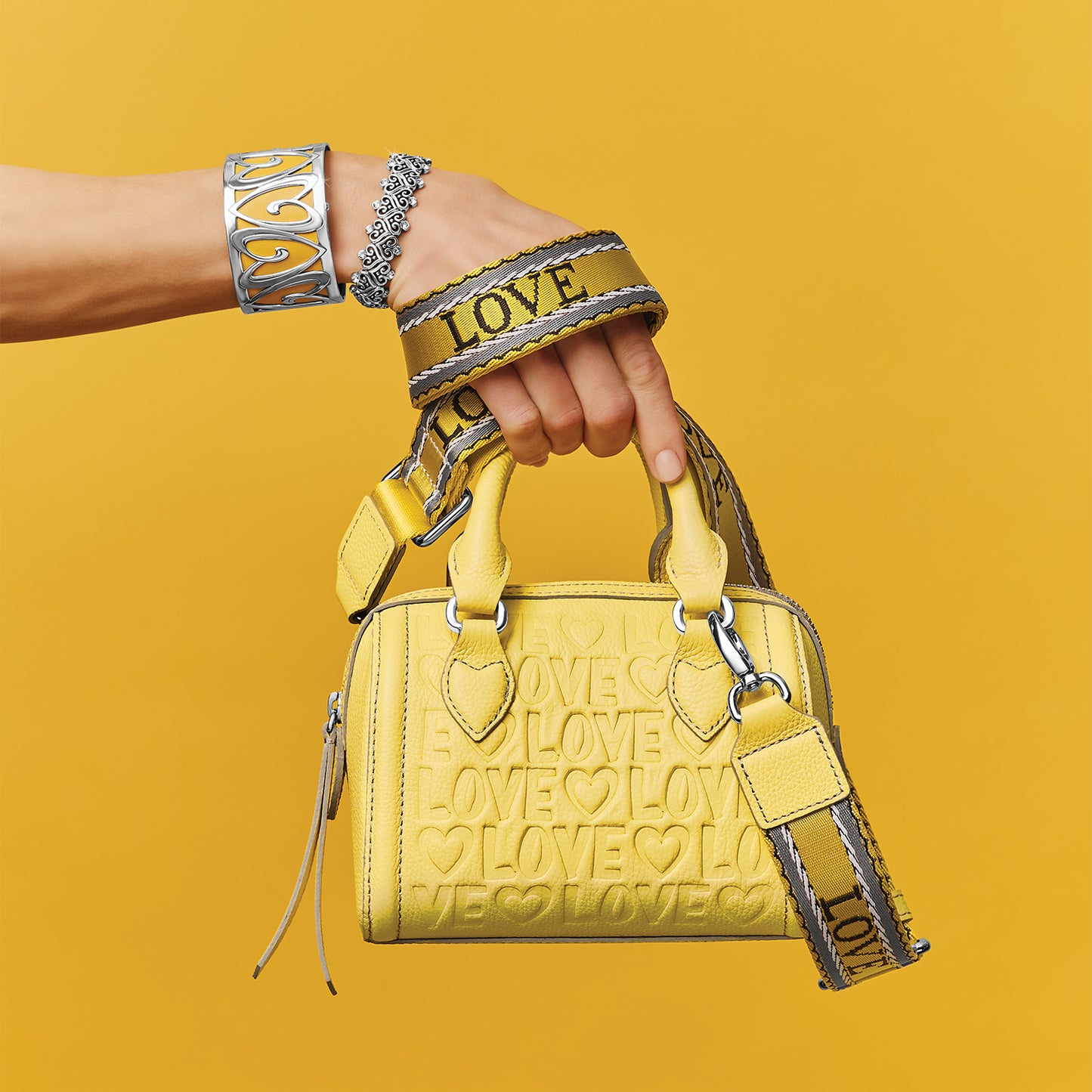 Model with a Brighton yellow leather handbag featuring embossed LOVE print and matching webbed shoulder strap