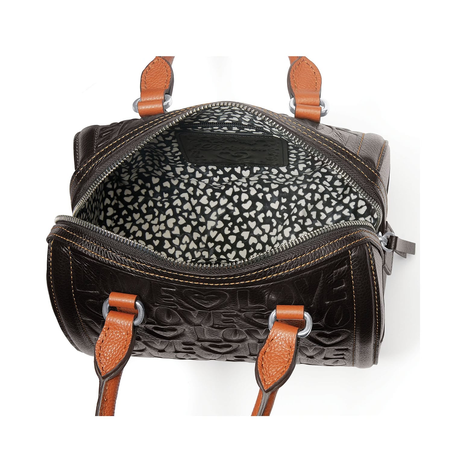 Close-up of Brighton handbag interior with heart-print lining, embossed leather exterior, and cognac leather handles