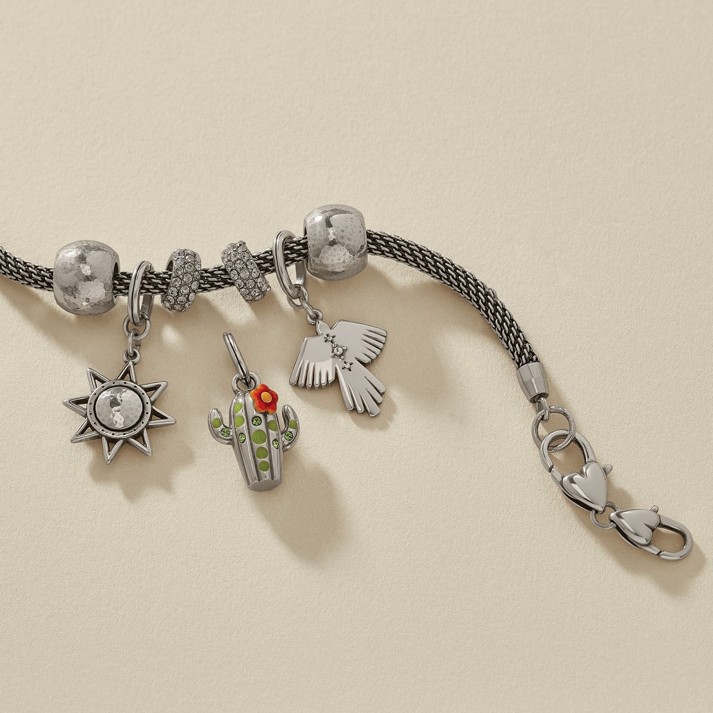 Brighton silver-plated charm bracelet styled with star, enamel cactus, and thunderbird charms on a neutral background