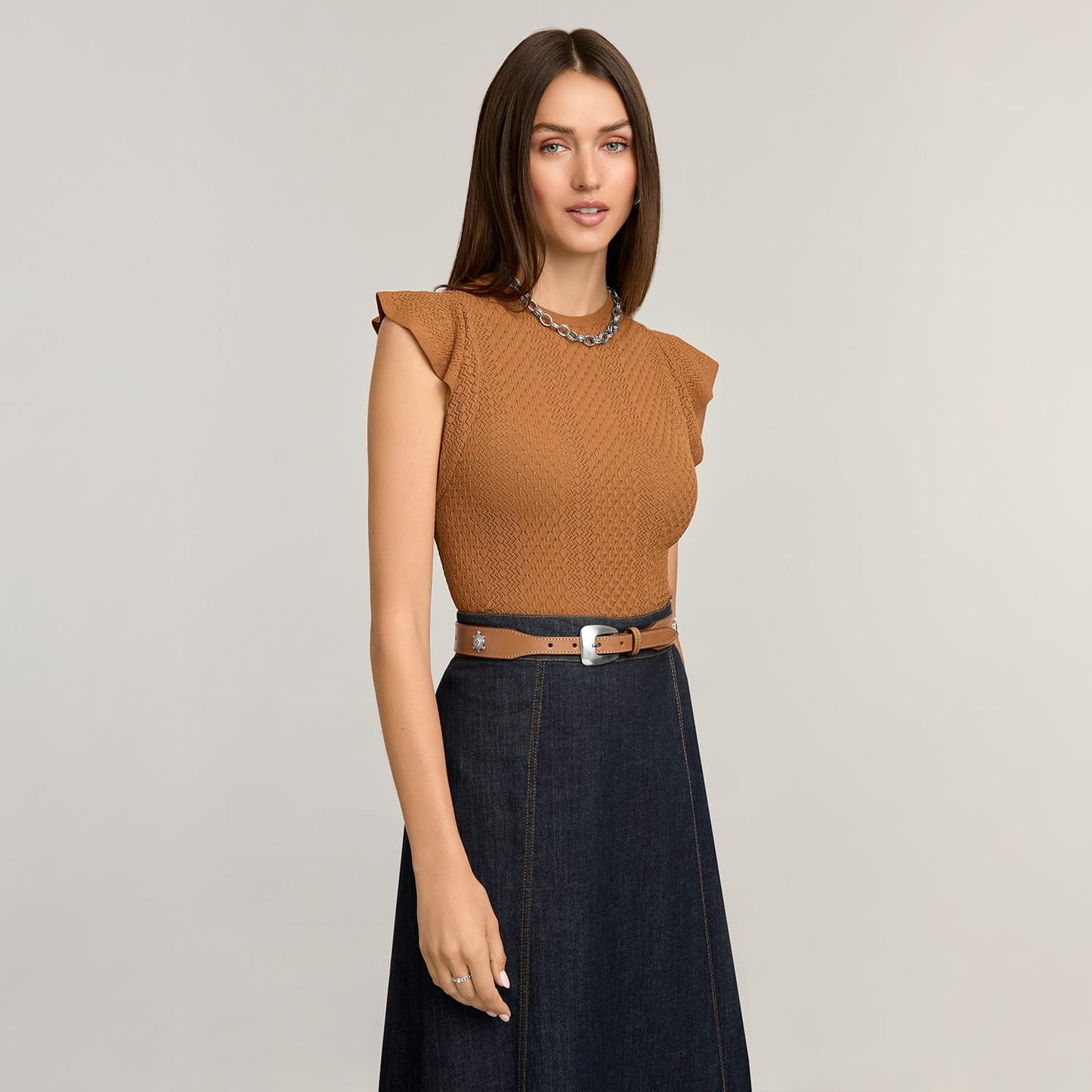 Model wearing a Brighton leather belt with silver-tone buckle and decorative stud detail over a denim skirt