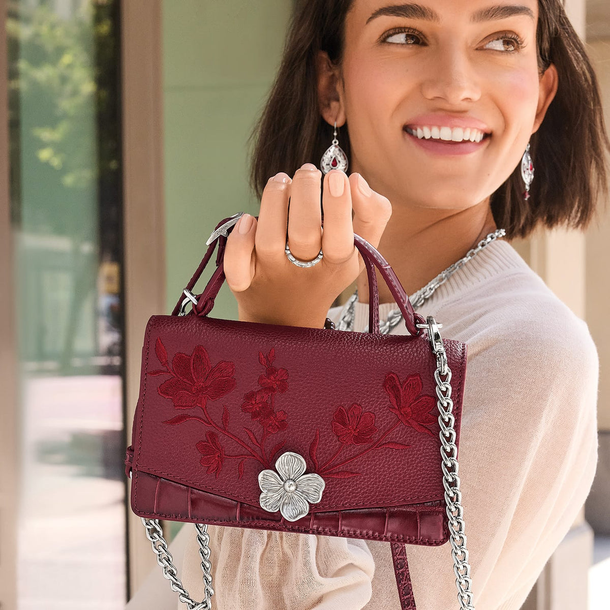 Brighton burgundy leather handbag with red floral embroidery, silver flower accent, and silver chain strap