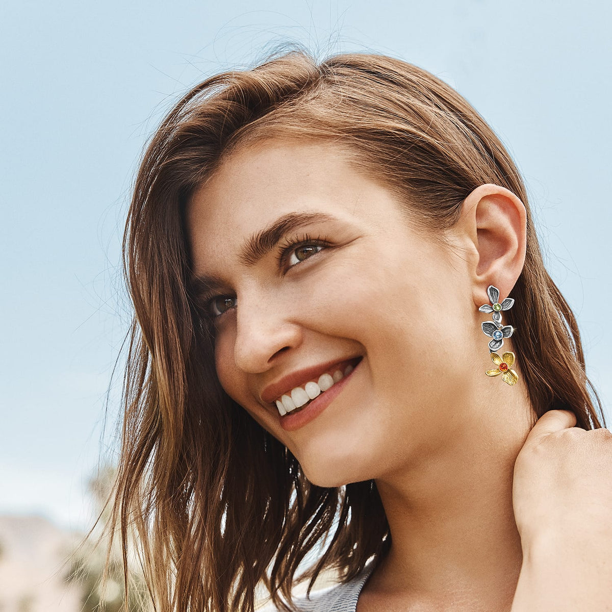 Model wearing Brighton two-tone flower drop earrings with green, blue, and red crystal centers