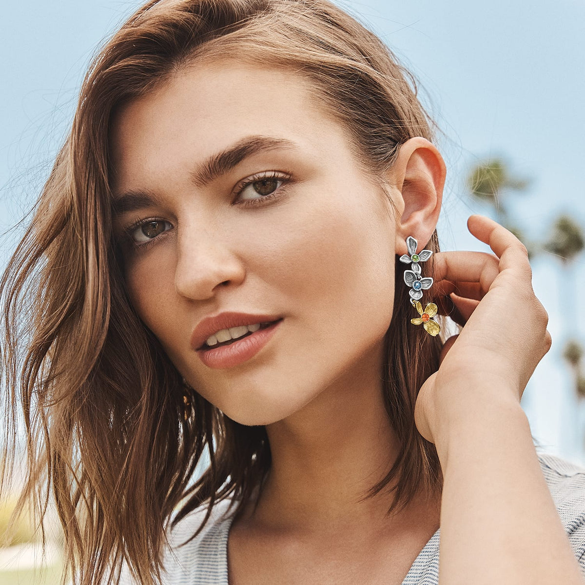 Model wearing Brighton two-tone drop earrings with silver and gold floral design and colorful crystal centers