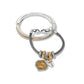 Brighton two-tone bangle and charm bracelet with crystal accents, cross charm, and medallion on a white background