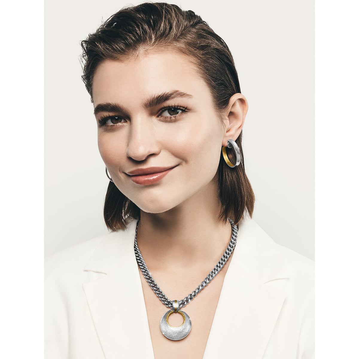 Model wearing a Brighton two-tone silver and gold pendant necklace on curb chain paired with matching hoop earrings