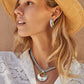 Model wearing a Brighton two-tone hammered pendant necklace on silver chain paired with matching two-tone hoop earrings