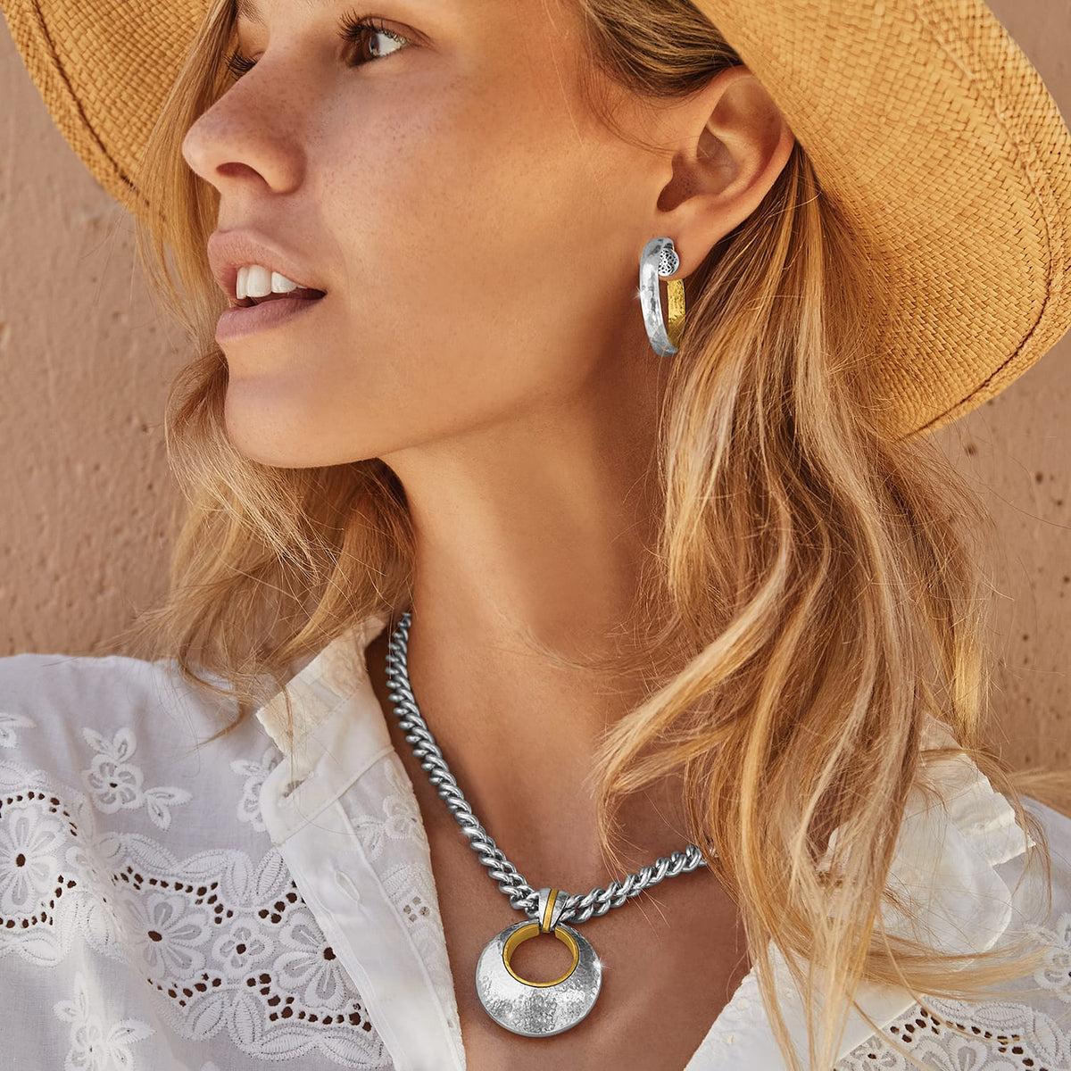 Model wearing a Brighton two-tone hammered pendant necklace on silver chain paired with matching two-tone hoop earrings
