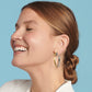 Model wearing a Brighton two-tone hoop earring with hammered silver and gold finish and small medallion accent