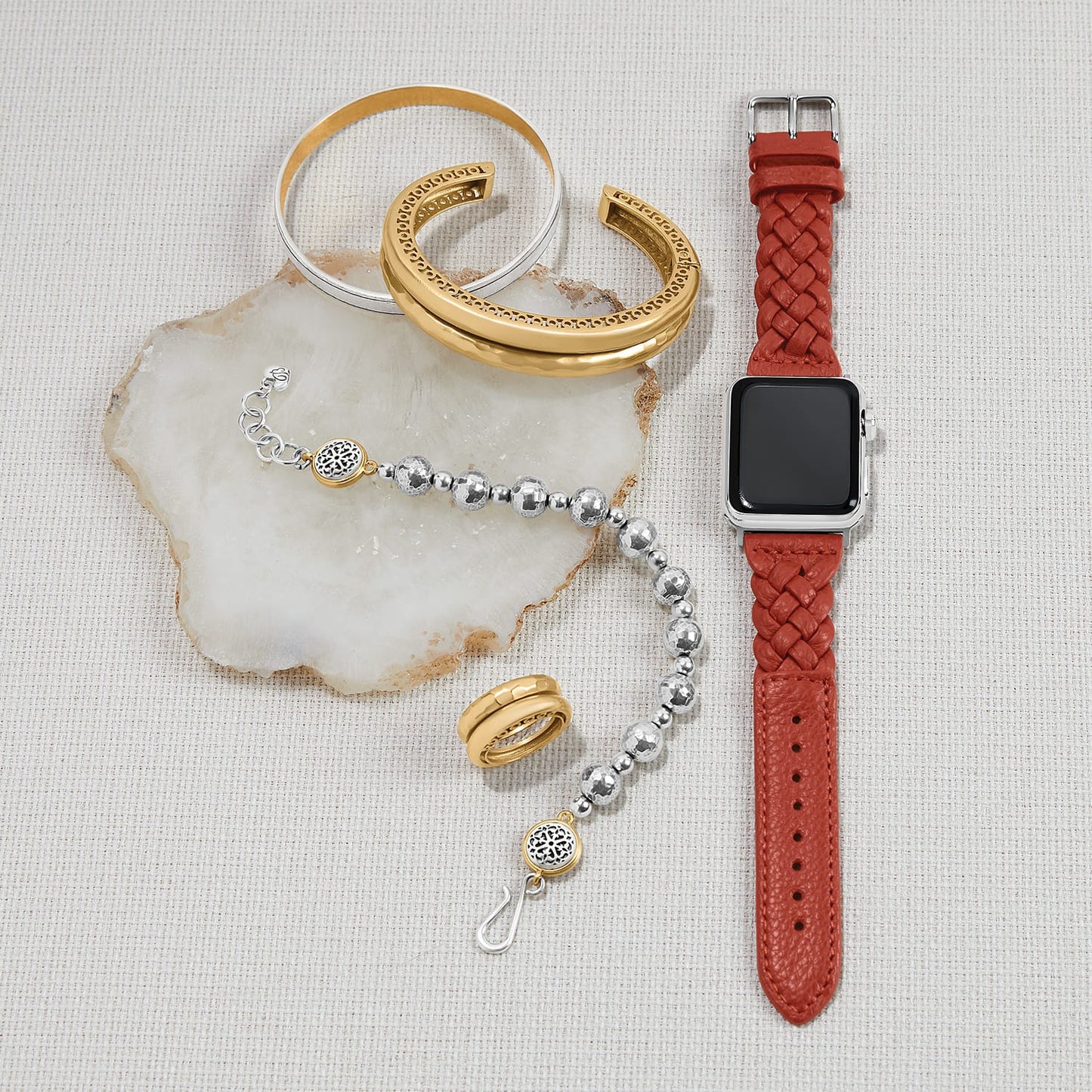 Brighton watch band in braided red leather styled with two-tone cuff bracelets and beaded bracelet on stone.
