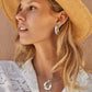 Model wearing Brighton two-tone hammered hoop earrings paired with a matching silver and gold circle pendant necklace