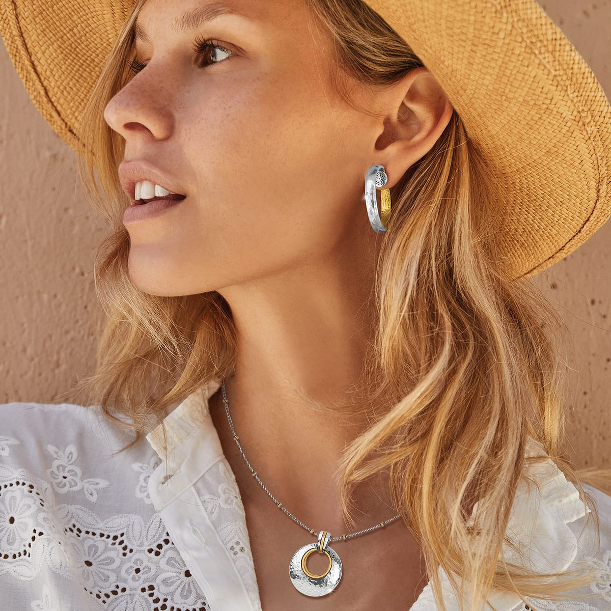 Model wearing Brighton two-tone hammered hoop earrings paired with a matching silver and gold circle pendant necklace