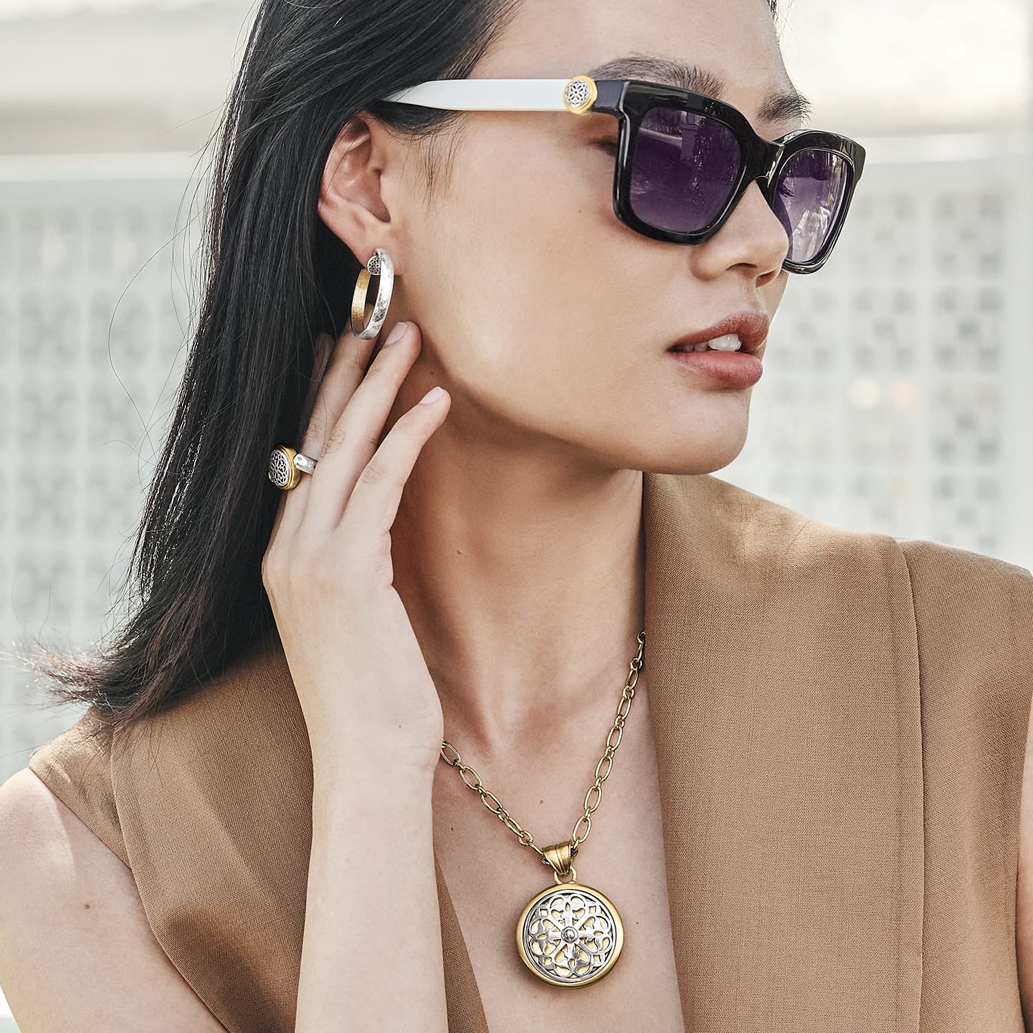 Model wearing a Brighton two-tone medallion pendant necklace with coordinating Brighton accessories including hoop earrings and ring
