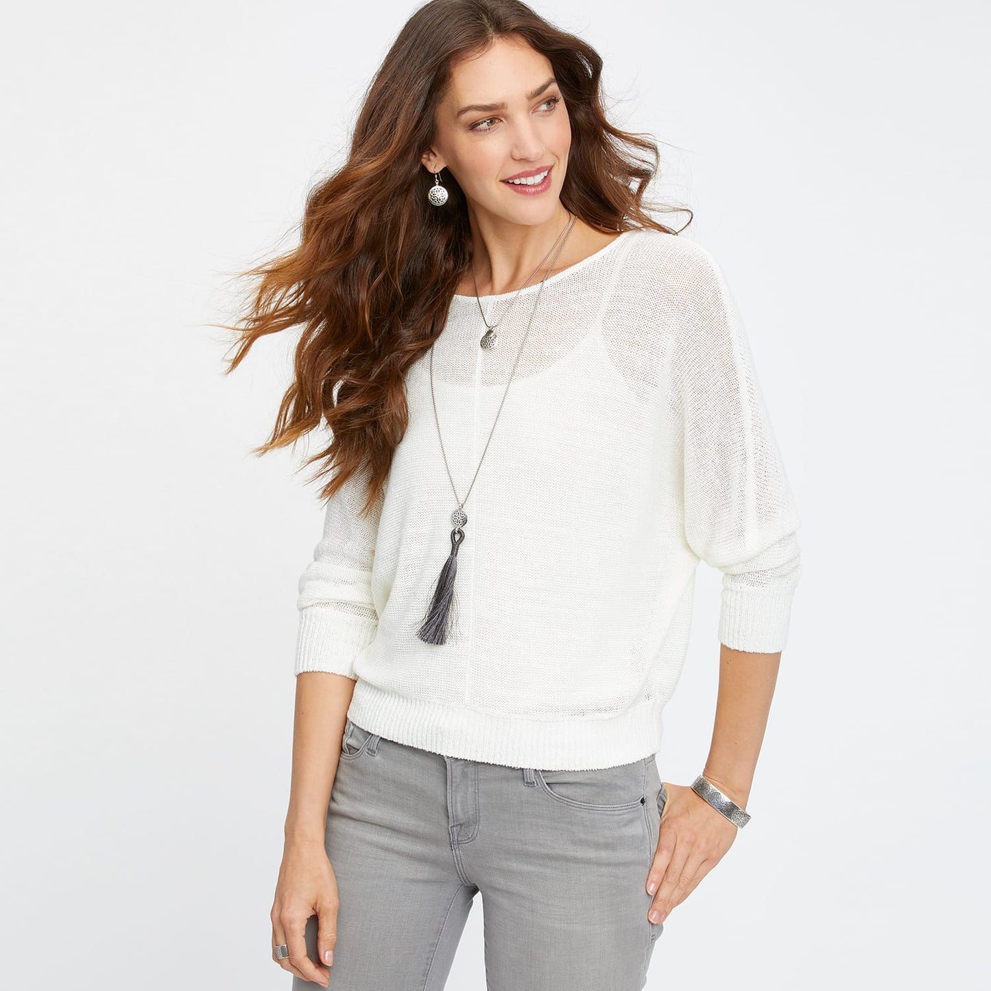 Model wearing a Brighton long tassel pendant necklace with silver-plated medallion accents and dark gray tassel