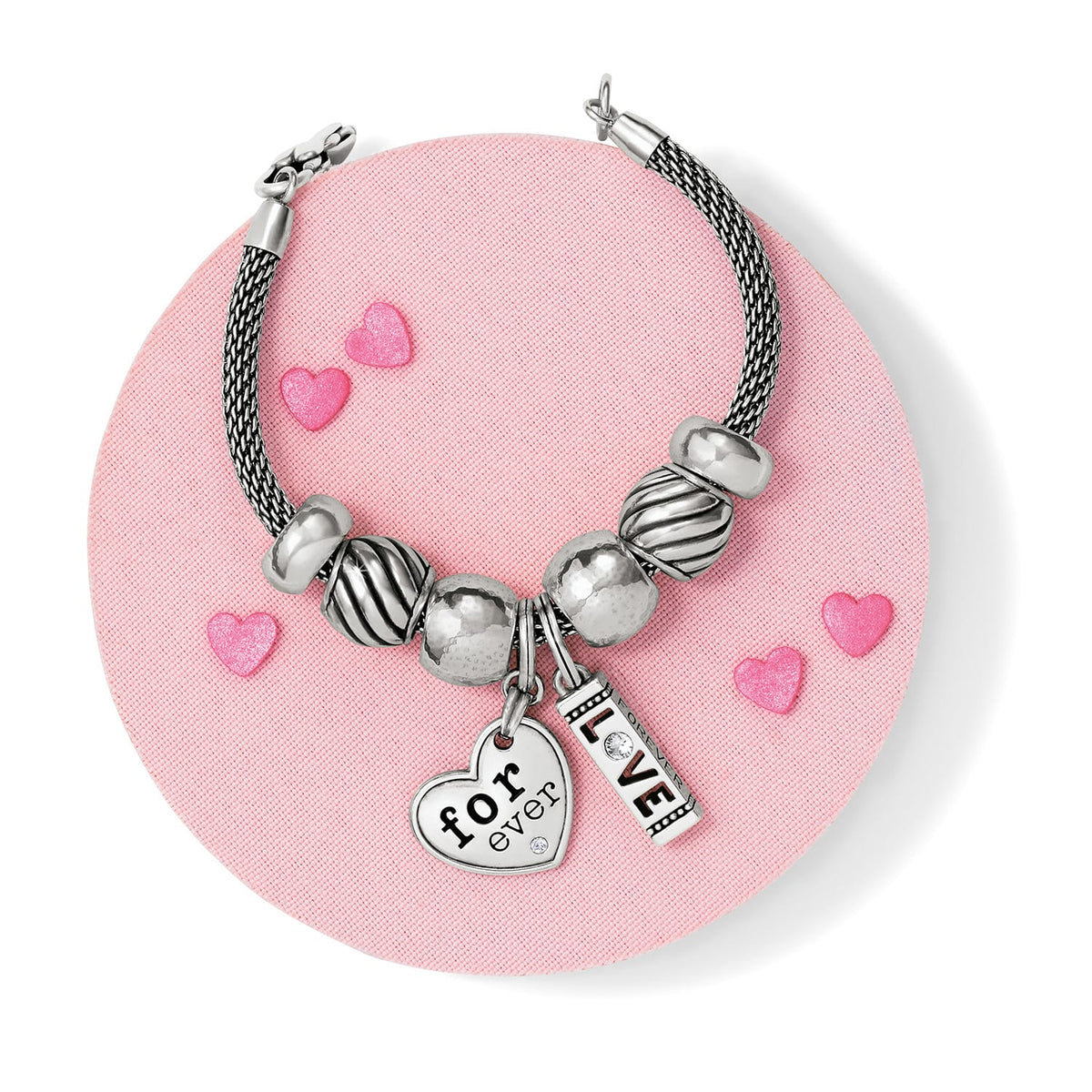 Brighton silver-plated beaded charm bracelet styled with heart and love charms on a pink background