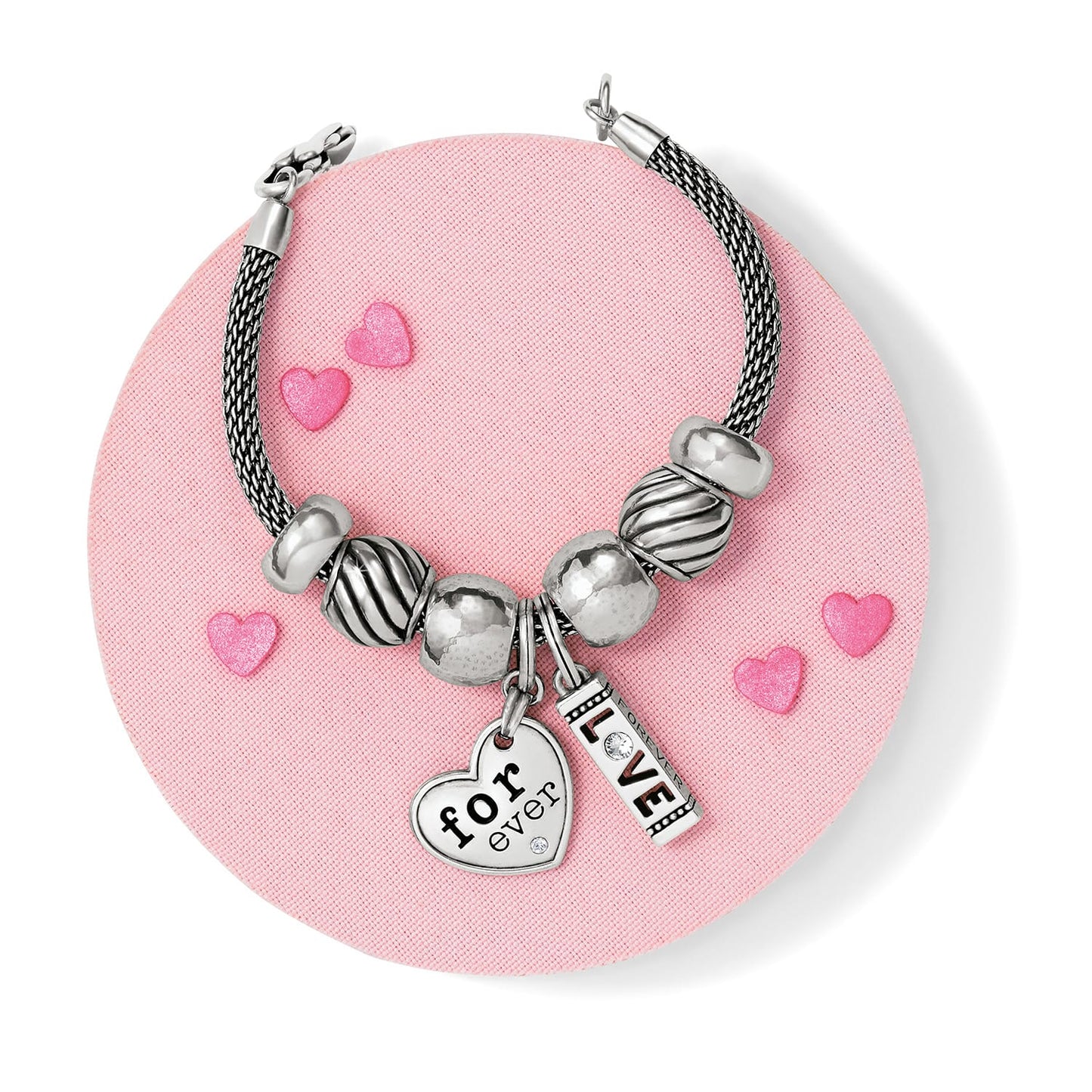 Brighton silver-plated beaded charm bracelet styled with heart and love charms on a pink background