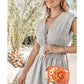 Model with a Brighton orange crossbody handbag featuring a floral print and dimensional rose with silver-tone chain strap
