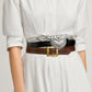 Model wearing three stacked Brighton leather belts with silver studded strap, black croc-embossed heart buckle, and brown tooled design