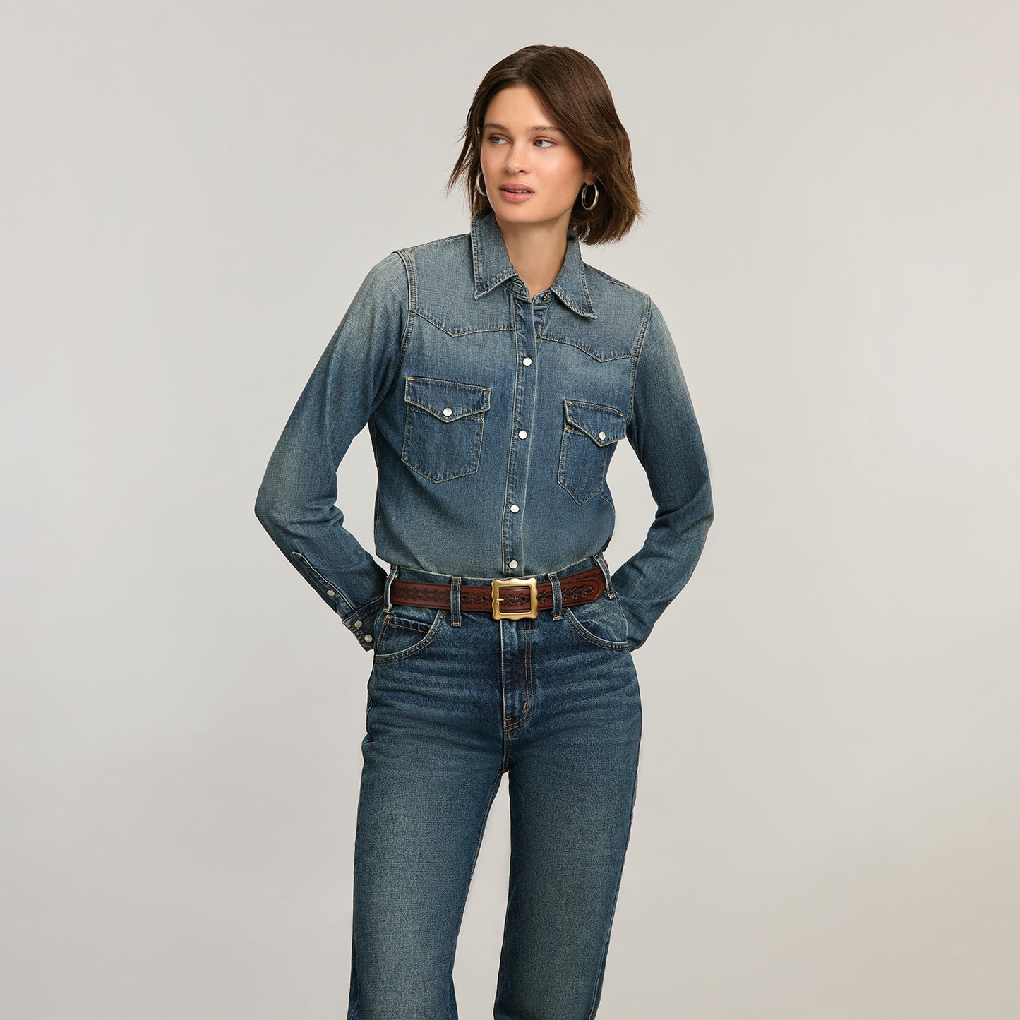 Model wearing a Brighton brown leather belt with tooled detailing and gold-tone rectangular buckle over denim