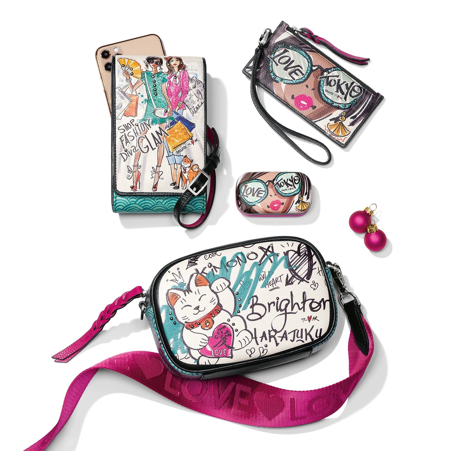 Brighton crossbody bag with illustrated cat and graffiti print, styled with a wristlet and other accessories.