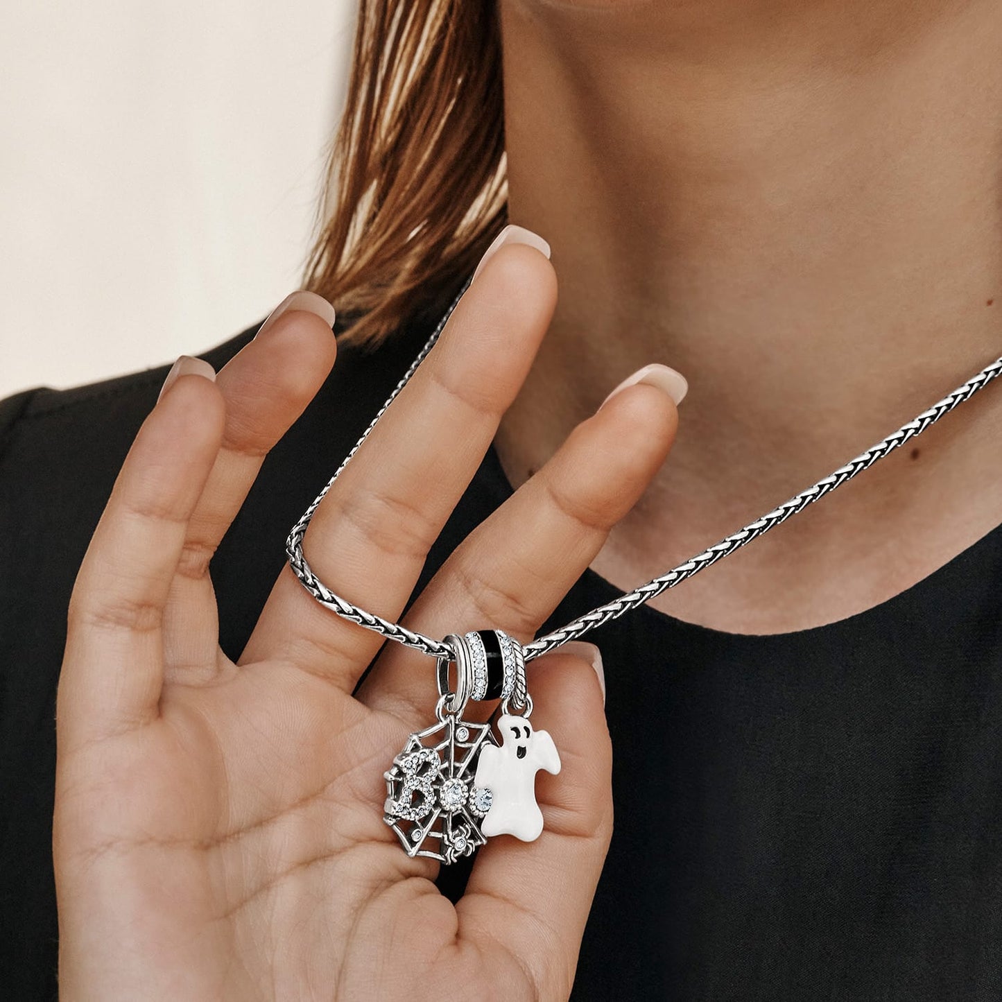 Model wearing a Brighton silver-plated necklace with spiderweb charm, white enamel ghost, and crystal accents