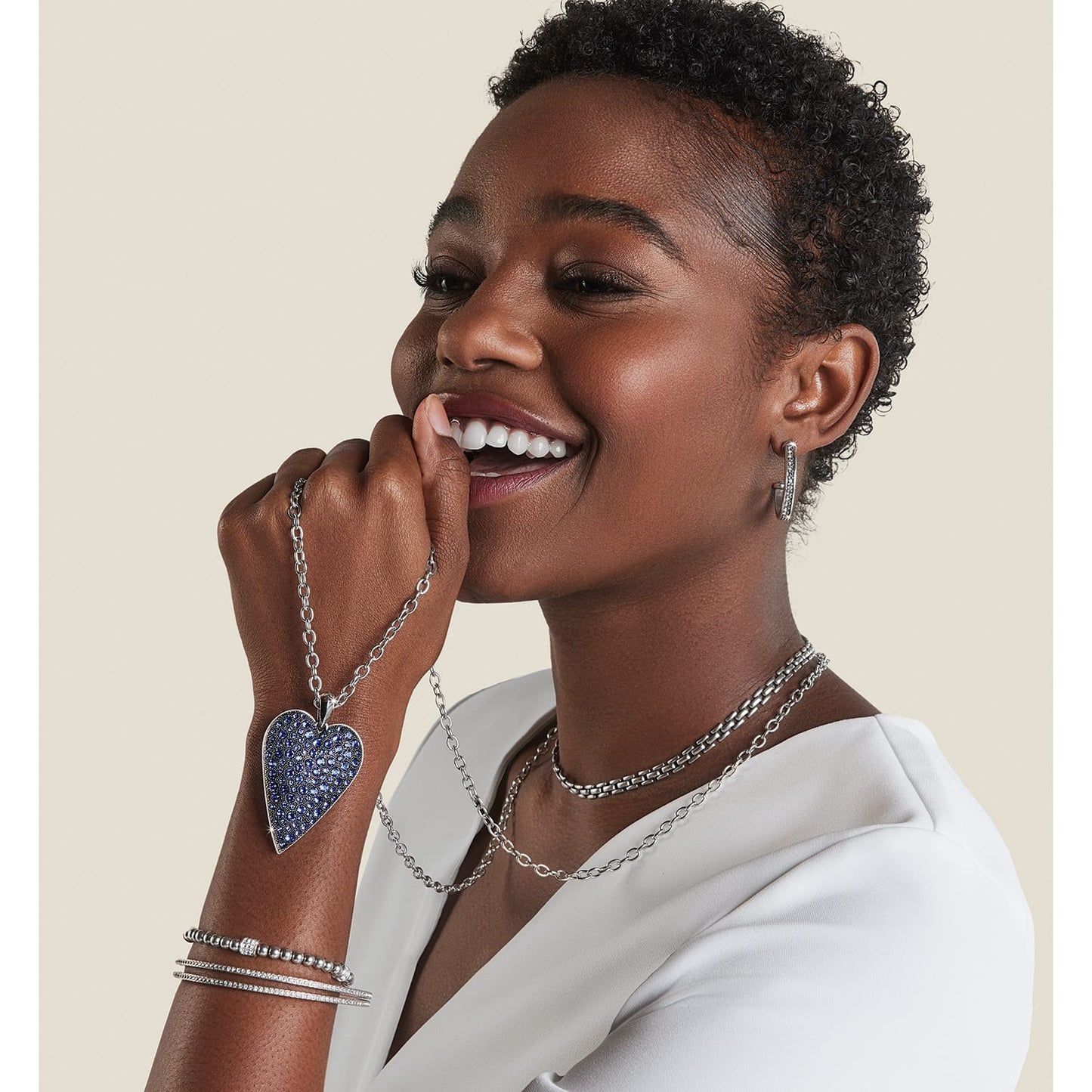 Model wearing a Brighton silver-plated heart pendant necklace with blue crystals and coordinating Brighton accessories