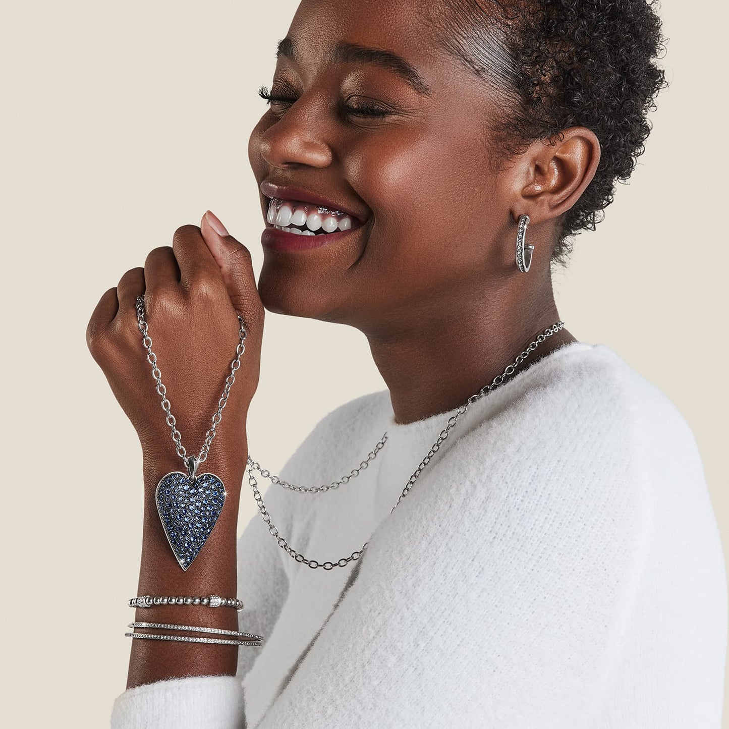 Model wearing a Brighton silver-plated heart pendant necklace with blue crystals and coordinating Brighton accessories