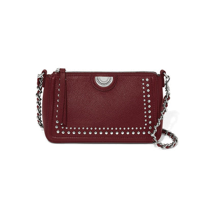 Brighton burgundy leather crossbody handbag with silver-tone studs, medallion accent, and woven chain strap on a white background