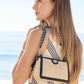 Model with a Brighton woven straw handbag featuring black leather trim and silver-tone chain shoulder strap
