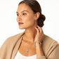 Model wearing a Brighton two-tone cross pendant necklace with coordinating Brighton stud earrings and charm bracelet