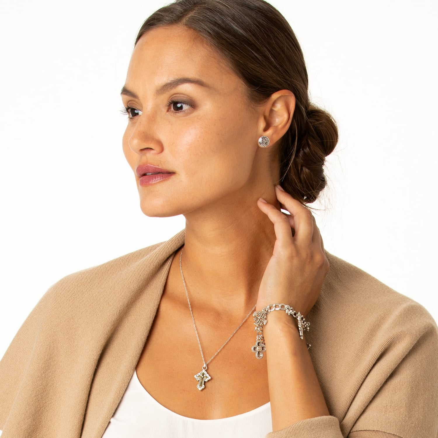 Model wearing a Brighton two-tone cross pendant necklace with coordinating Brighton stud earrings and charm bracelet