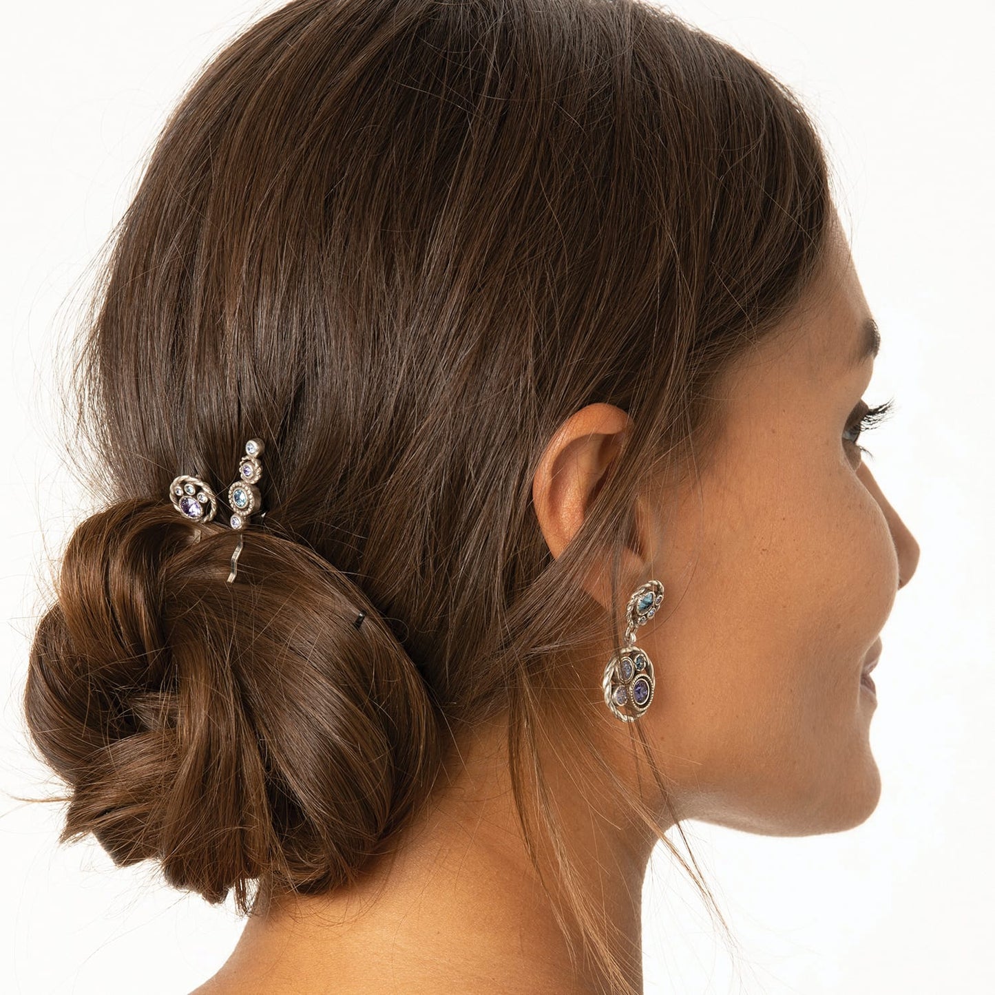 Model wearing Brighton silver-plated drop earrings with blue and purple crystals paired with a coordinating crystal hair pin