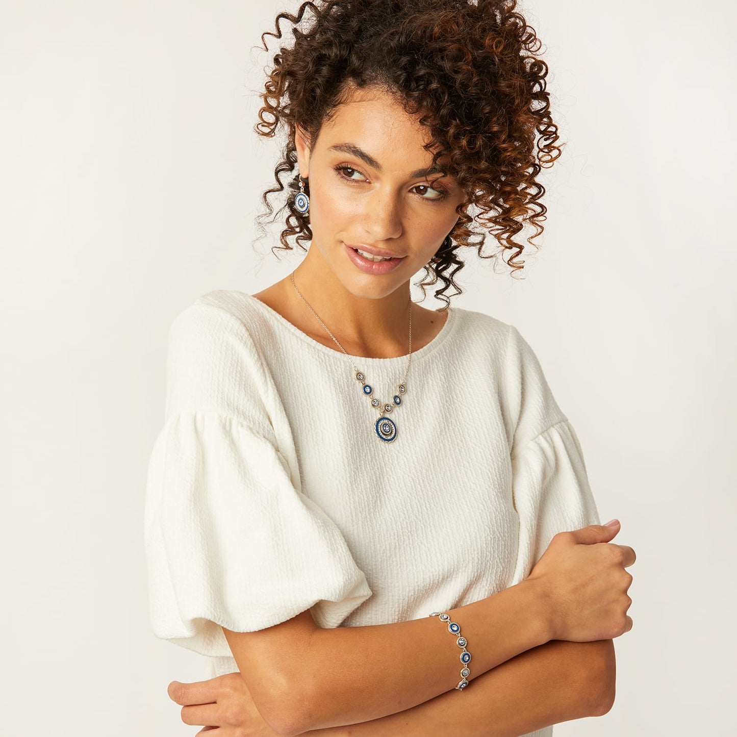 Model wearing a Brighton silver-plated pendant necklace with blue medallion accents and coordinating Brighton accessories