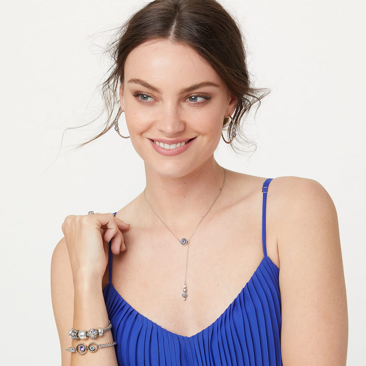 Model wearing a Brighton silver-plated Y-necklace with purple crystal pendants and coordinating Brighton accessories