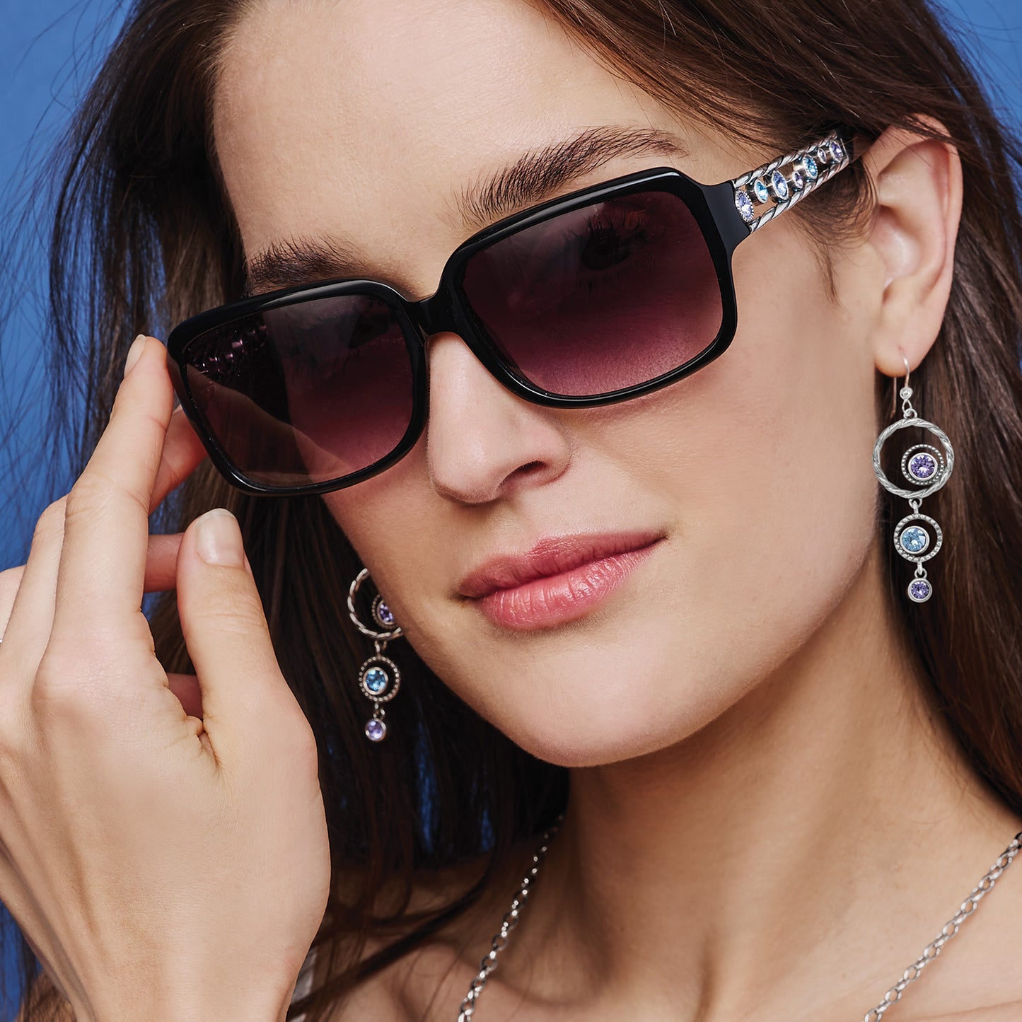 Model wearing Brighton black sunglasses with silver-plated temples and crystal accents, styled with coordinating Brighton drop earrings