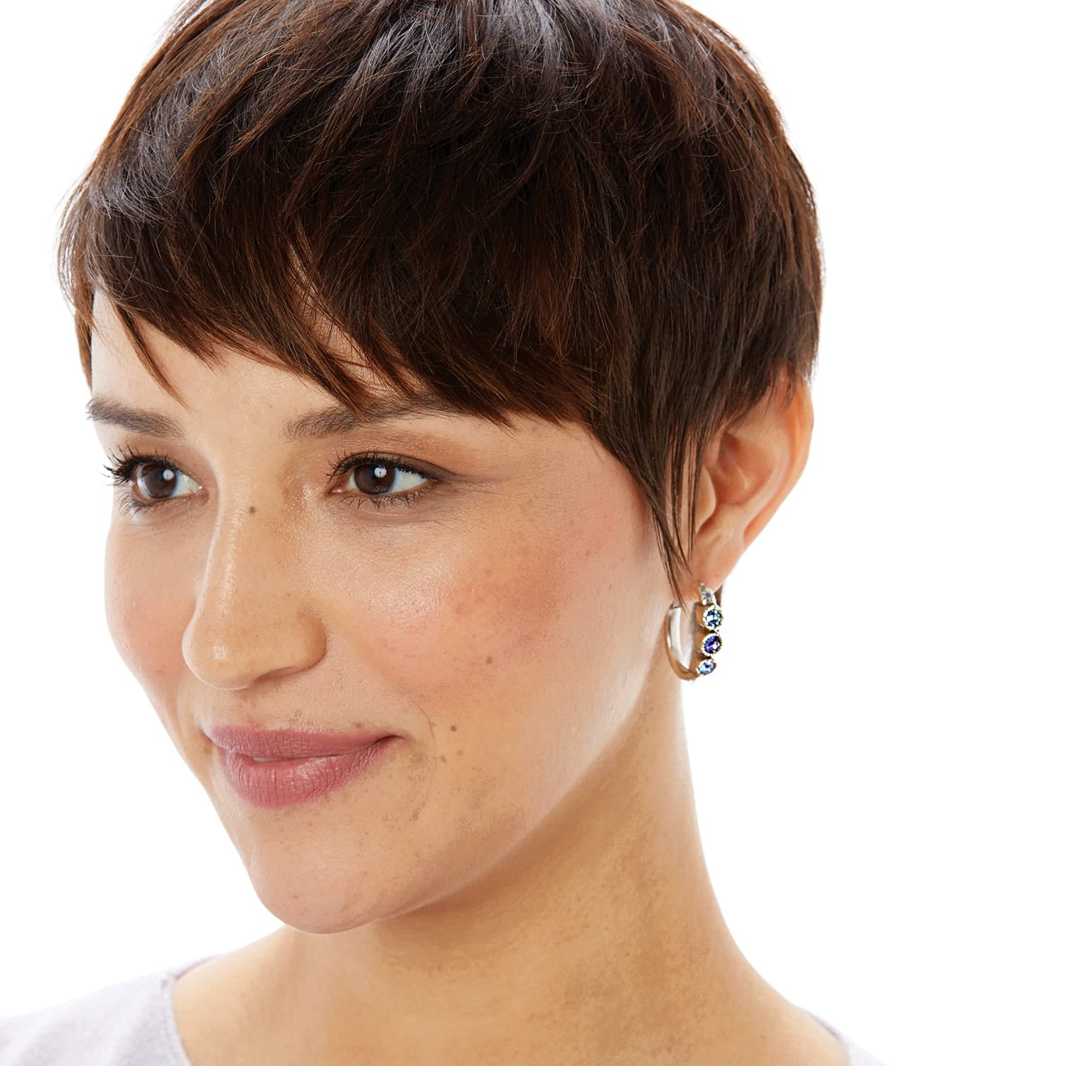Model wearing Brighton silver-plated hoop earrings with blue and purple crystal accents along the front