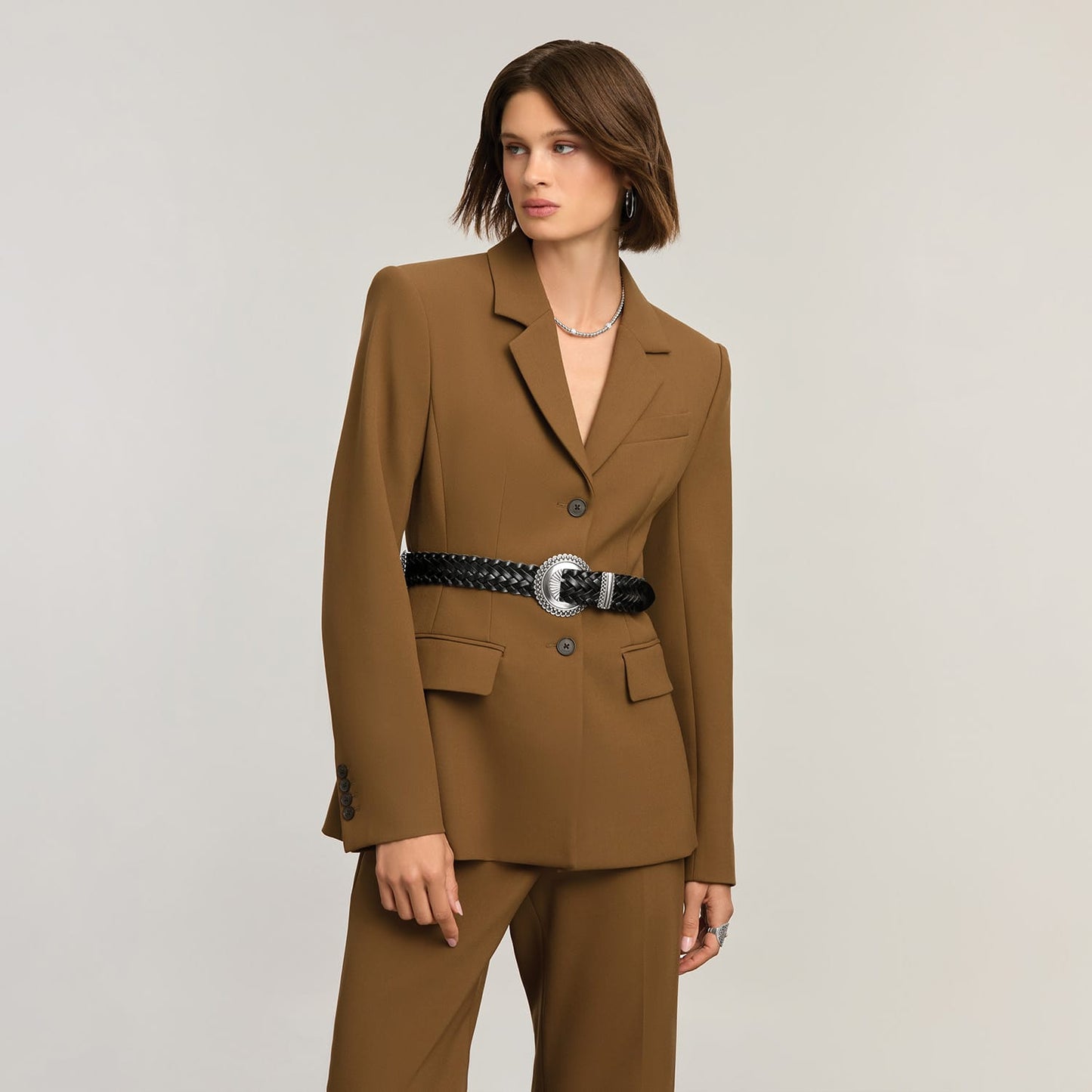 Model wearing a Brighton black braided leather belt with ornate silver-tone round buckle over a brown blazer