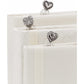 Brighton bookmarks with silver-plated heart-shaped charms in ornate scroll designs resting on ivory fabric books on a white background
