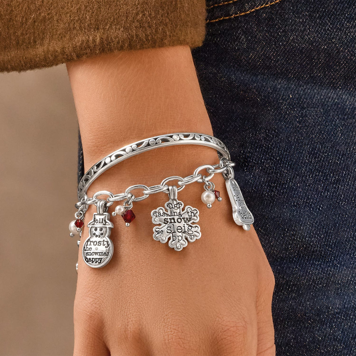 Model wearing a Brighton silver-plated bangle with holiday charms, red crystals, and glass pearl accents