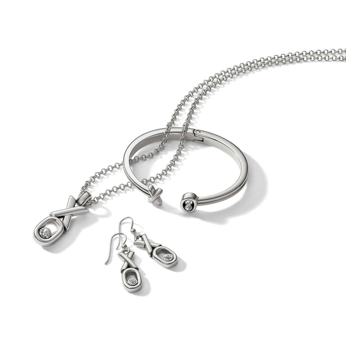 Brighton silver-plated XO necklace, drop earrings, and hinged cuff bracelet set with crystal accents on a white background