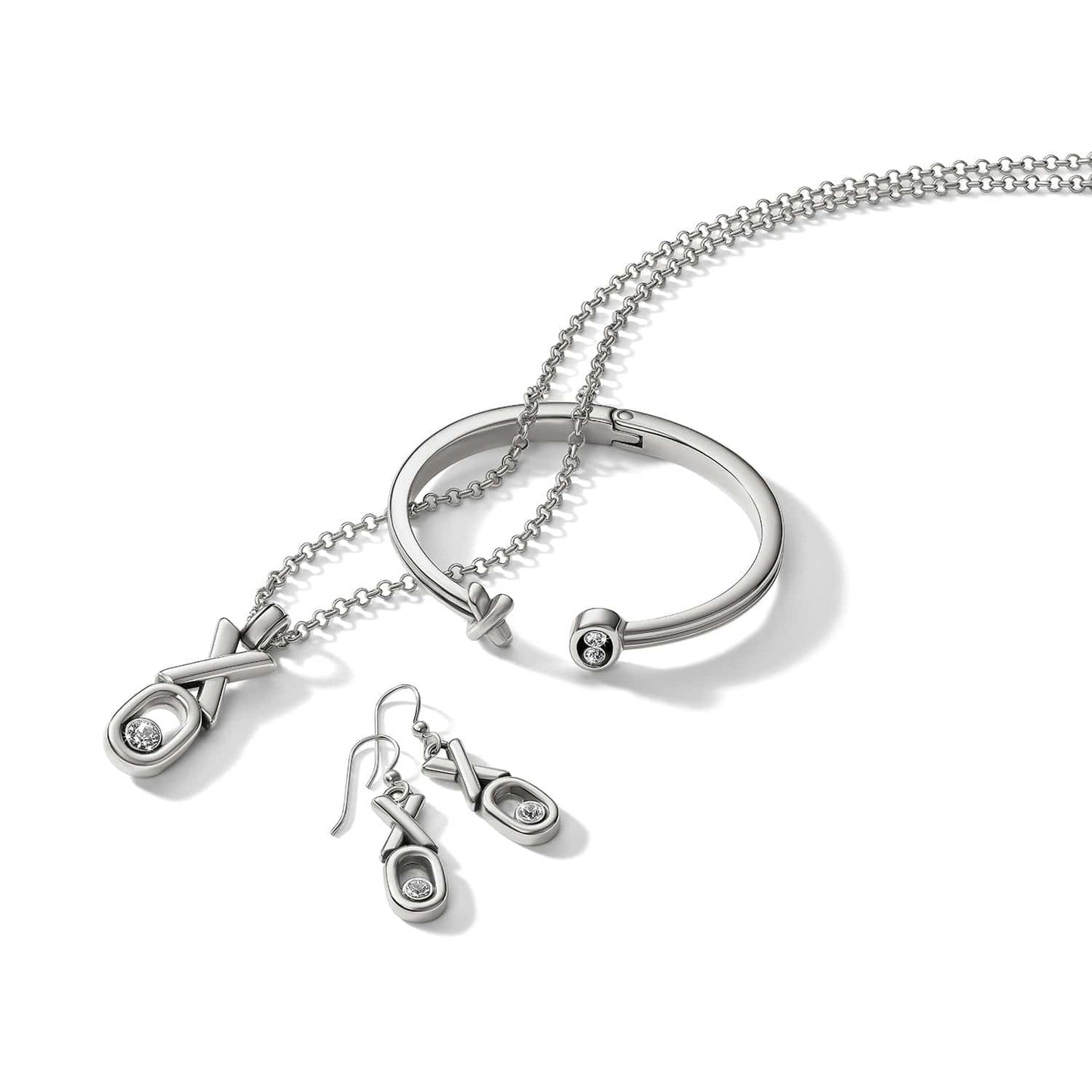 Brighton silver-plated XO necklace, drop earrings, and hinged cuff bracelet set with crystal accents on a white background