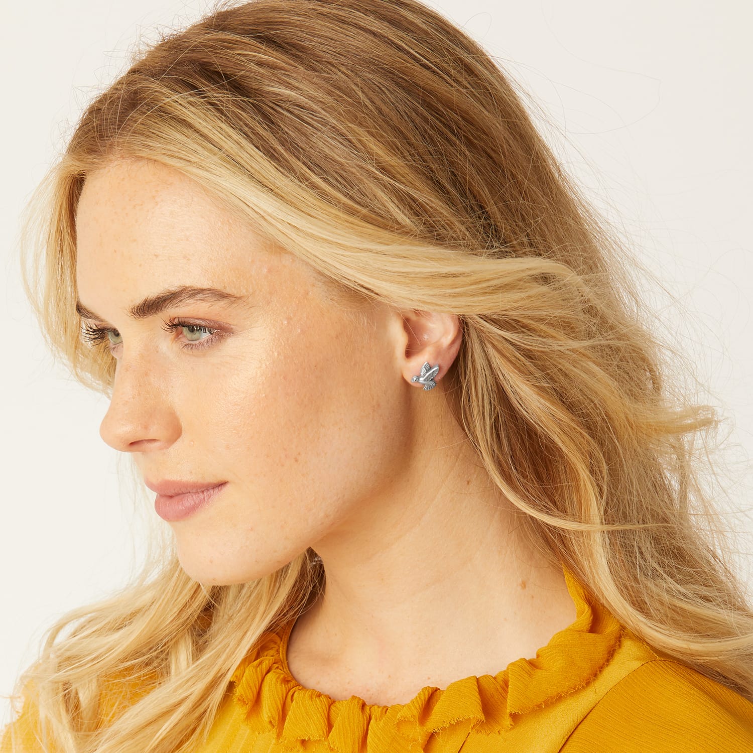 Model wearing a Brighton silver-plated stud earring featuring a small bird in flight design